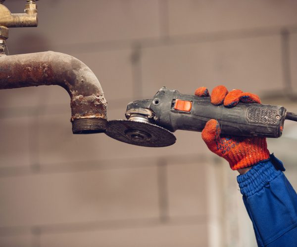 Closeup of repairman in uniform, professional builder working using construction equipment. Process of building, apartment renovation, repairing, building. Coloring, measuring, preparing the base.